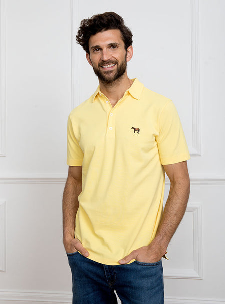 Man wearing lemon yellow polo shirt in 100% cotton with Newmarket 875 horse logo embroidered on the front.